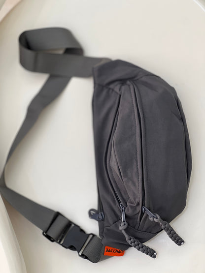 Nylon fanny pack with double zippered compartments and braided zipper pulls.