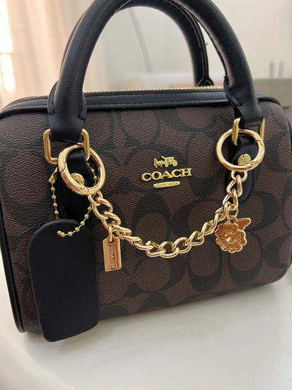Coach Mini Rowan Crossbody Bag in Signature Canvas, detailed with a playful gold-tone chain charm strap and a structured, compact silhouette with box