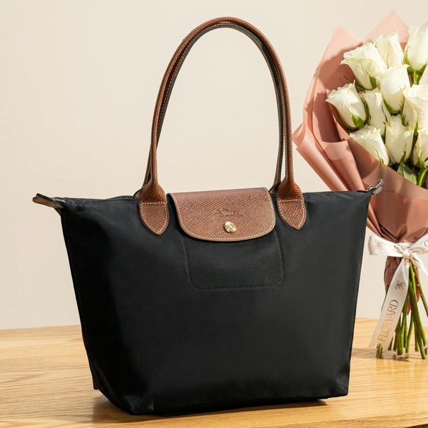 Longchamp Le Pliage tote bag featuring brown leather handles and a gold-tone snap closure