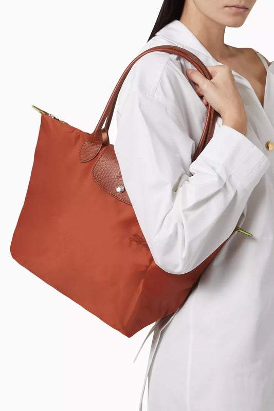 Longchamp Le Pliage tote bag featuring brown leather handles and a gold-tone snap closure