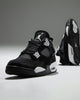 Air Jordan 4 "White Thunder" sneakers, featuring a sleek black nubuck upper contrasted by crisp white mesh accents