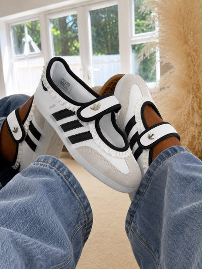 Samba Jane sneakers in white and black, featuring a distinctive midfoot strap and delicate ruffled trim