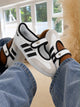 Samba Jane sneakers in white and black, featuring a distinctive midfoot strap and delicate ruffled trim