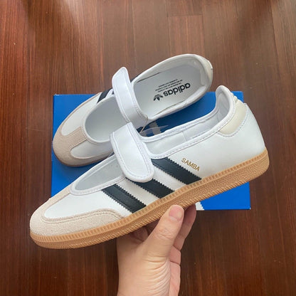 Samba Jane shoes featuring a white leather upper, black stripes, and a velcro strap